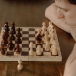 A focused young man planning a chess move in a cozy home setting, conveying strategy and concentration.
